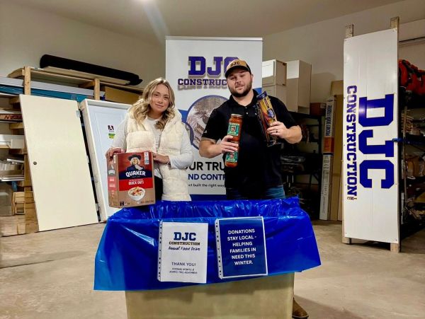 Two people holding food donations in a warehouse.