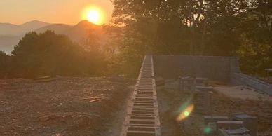Sunset over a construction site near trees and mountains.