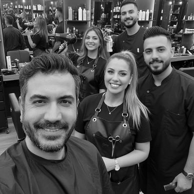 A happy group of hairdressers posing inside a salon.