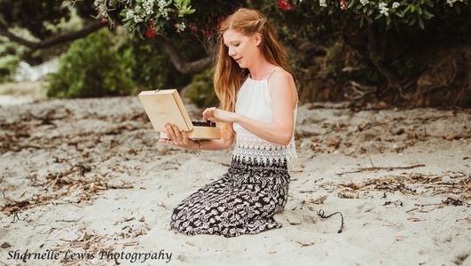 Female kneeling in sand with a doTERRA essential oils box