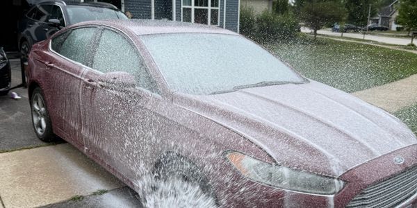 Car being washed with water spray.