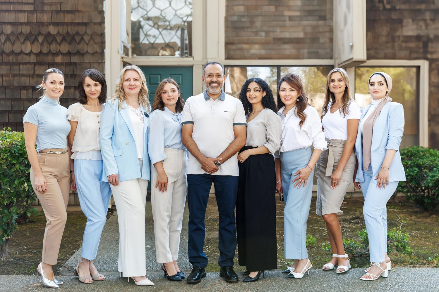 A diverse group of nine professionals posing outdoors in business casual attire.