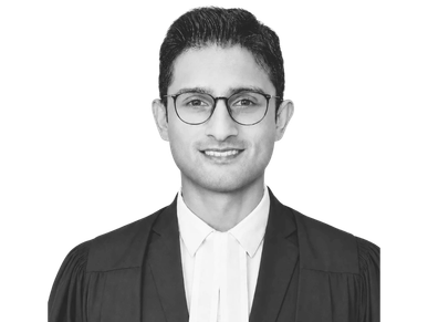 Portrait of a smiling man in formal legal attire and glasses.