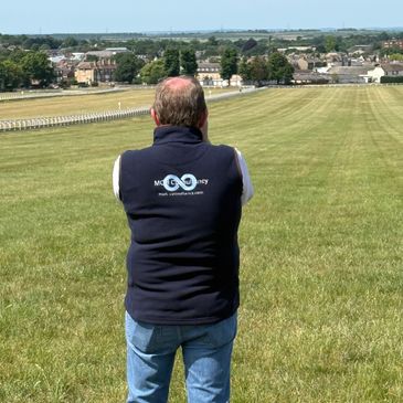 Man standing on a grassy hill overlooking a town.