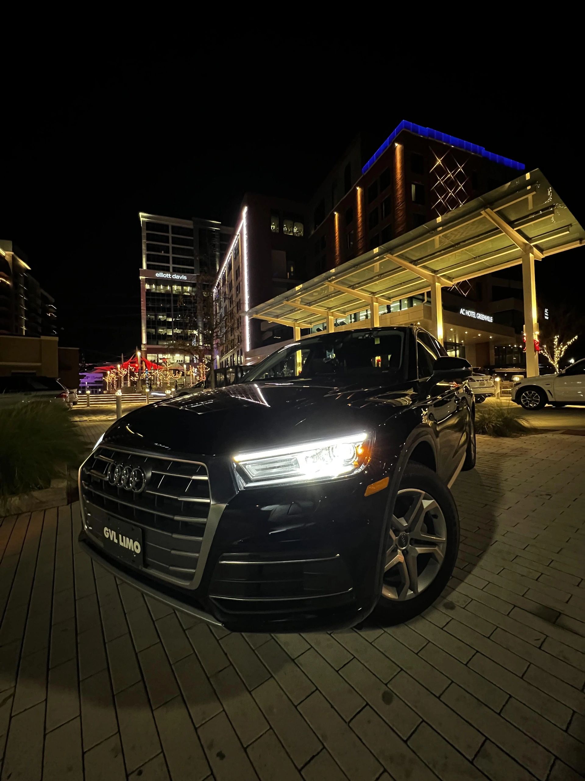 Black Audi car parked at night in a city setting.
