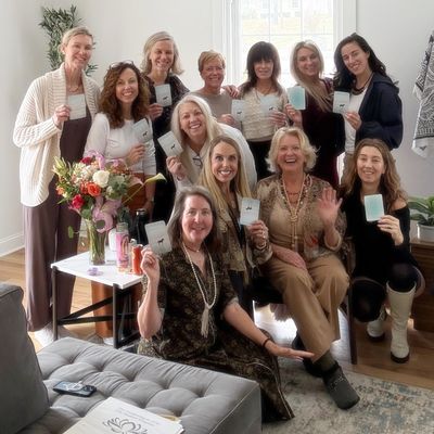 Group of women smiling and each holding up a card in a sunlit room