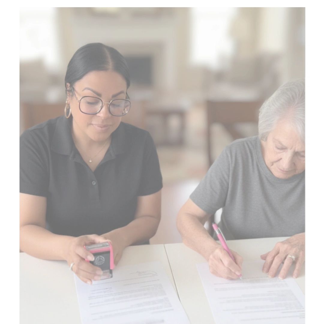 Two women signing and stamping official documents at a table.