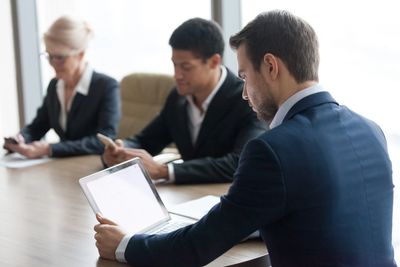 Businesspeople working intently on devices in a meeting room.