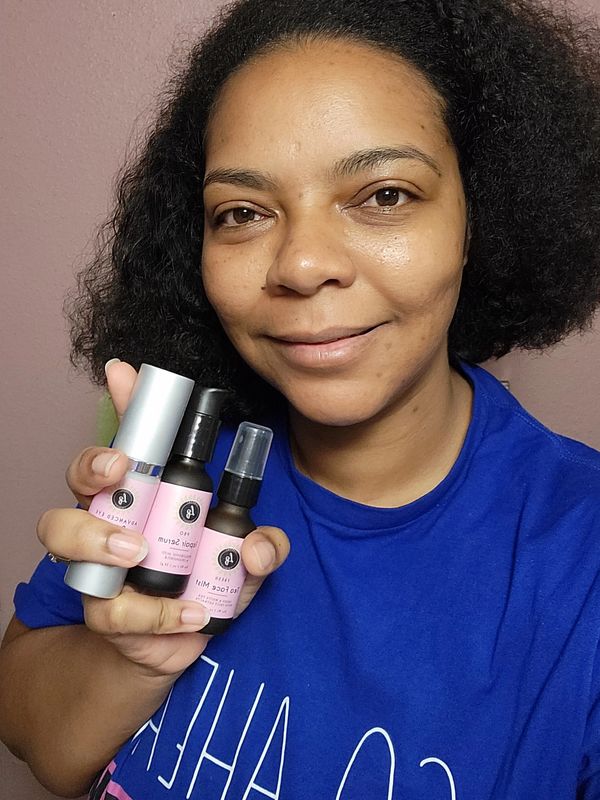 Woman holding three skincare products with a smile.