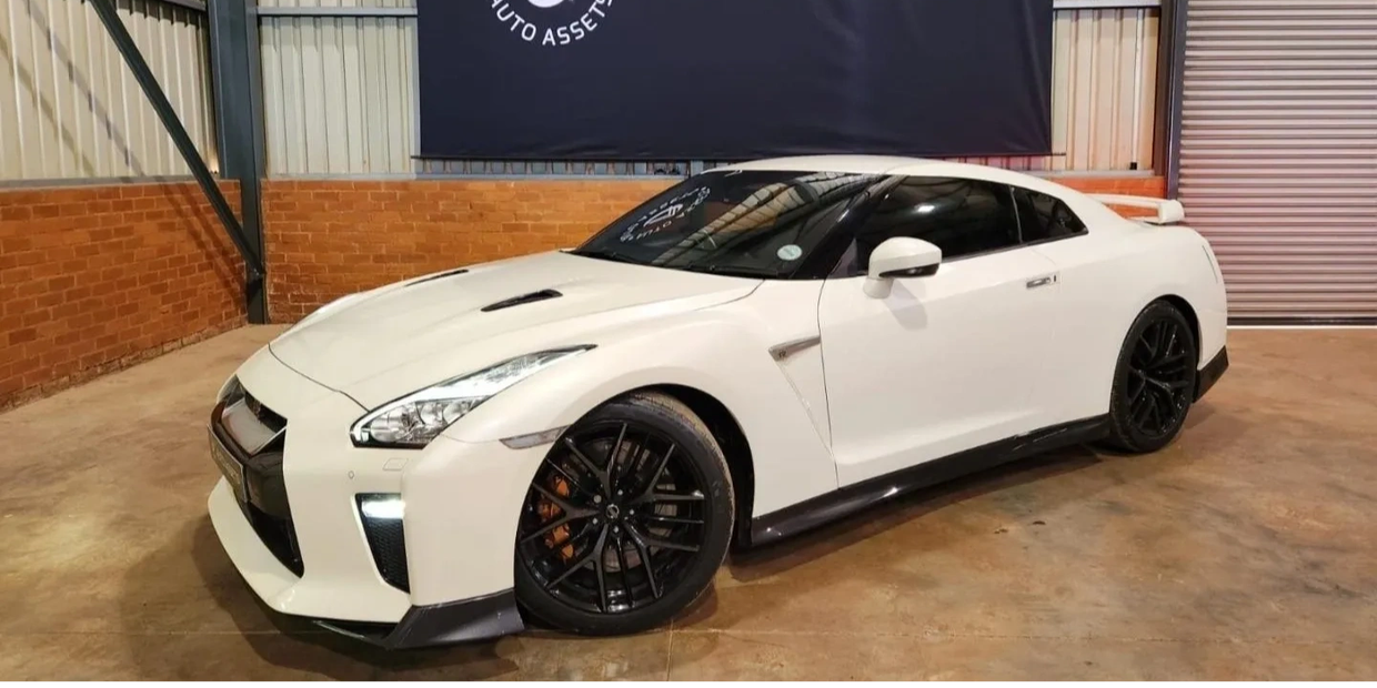 White Nissan GT-R sports car parked indoors with black rims.