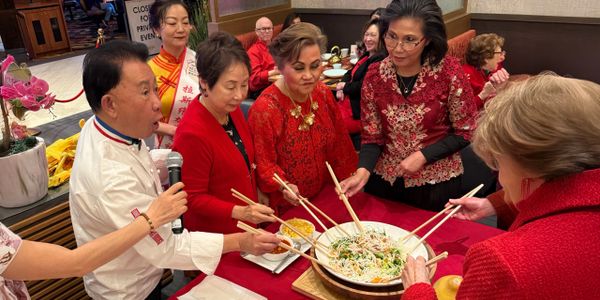 Martin Yan and customers use chopsticks to mix a salad