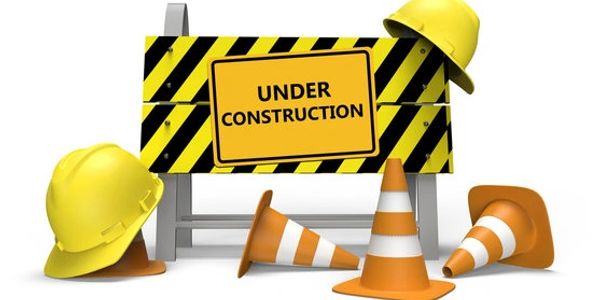 Under construction sign with cones and helmets.