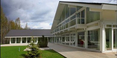 Modern house with large glass windows and a wooden deck under a cloudy sky.