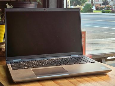 Dell laptop on a wooden table near a window.