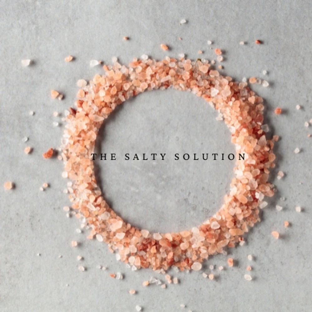 Pink Himalayan salt crystals arranged in a circle with text "THE SALTY SOLUTION".