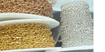 Spools of gold and silver chain links arranged on shelves.