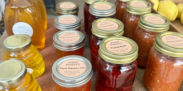 Jars of honey and a variety of canned goods are displayed on a table.