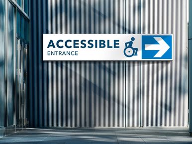 An accessible entrance sign with an image of a person in a wheelchair and an arrow