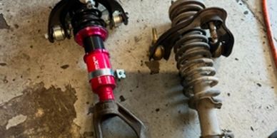 Two car coilover suspension assemblies on the floor.