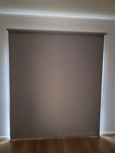 Closed dark brown roller blinds covering a window.