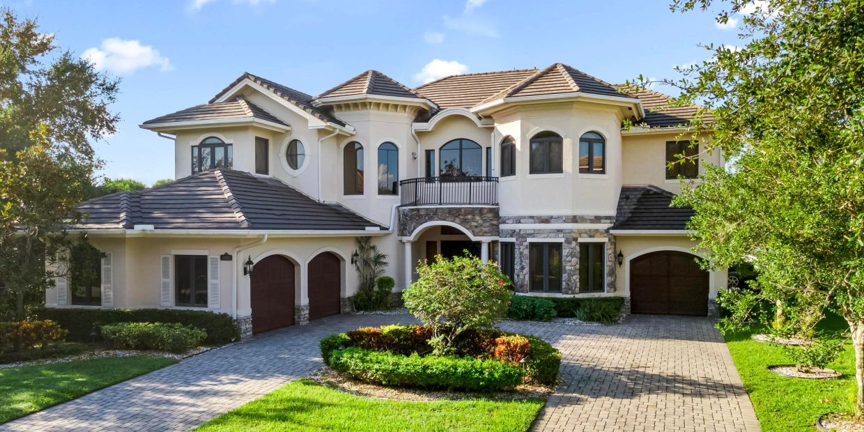 Luxurious two-story house with stone facade and landscaped front yard.