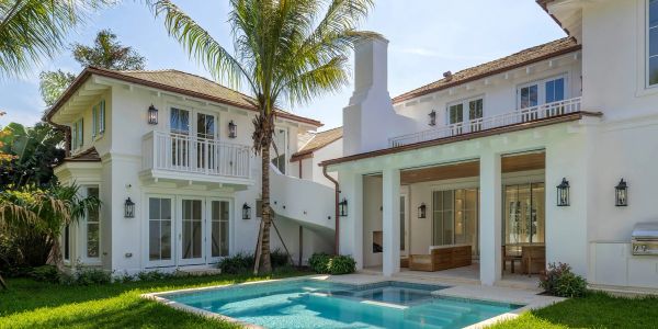 Modern white house with a pool and palm tree.