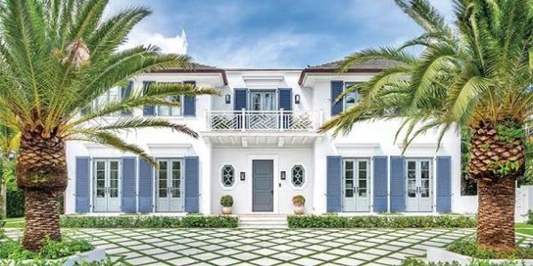 Elegant white two-story house with palm trees and a tiled driveway.