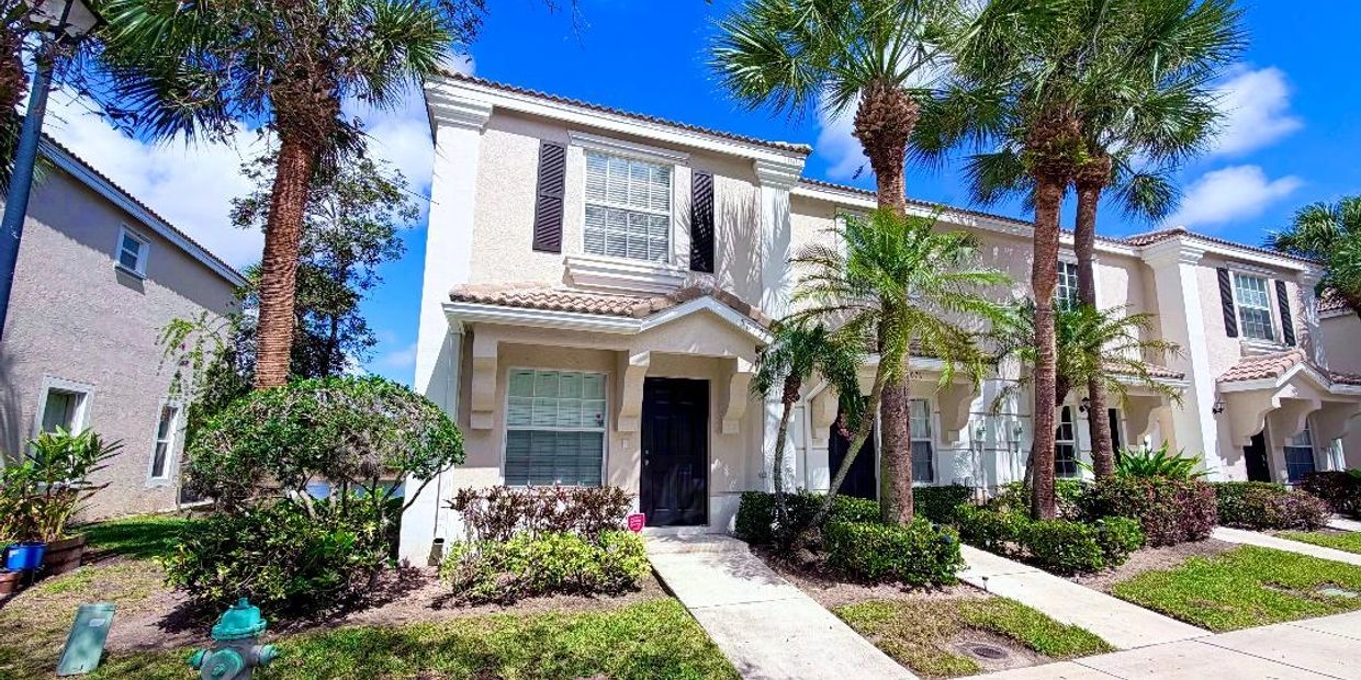 Townhouse with palm trees and blue sky.
