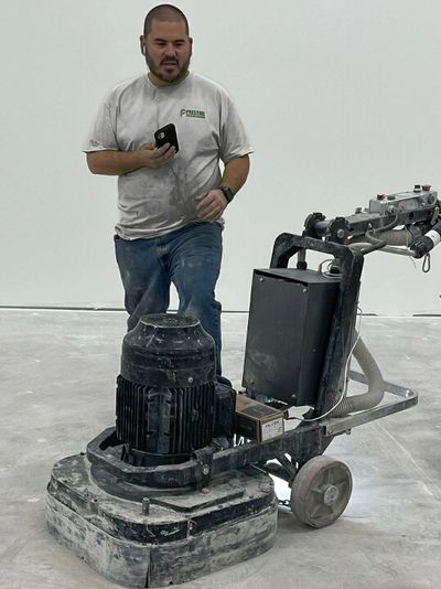 Miguel owner of macaw coatings with walk behind grinder with vacuum attached ready to prep the floor