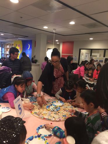 Children and an adult engaged in a group craft activity at a table.