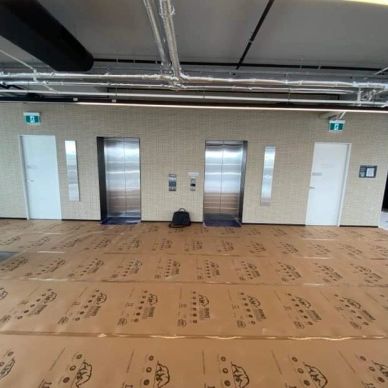 Elevator lobby with protective floor covering and a backpack.