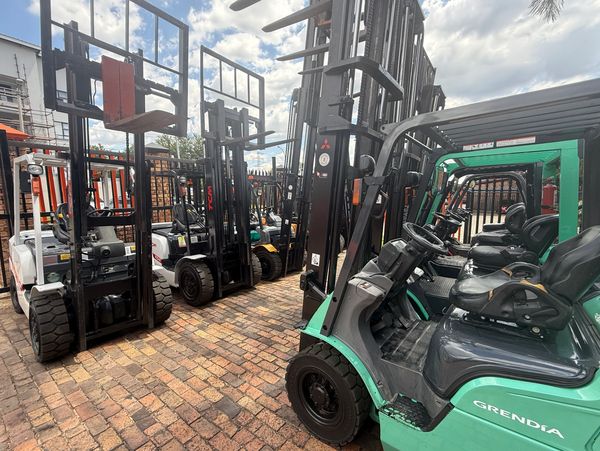 Row of parked forklifts lined up outdoors on a sunny day.