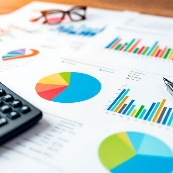 Colorful charts and graphs on printed financial documents with a calculator and glasses.