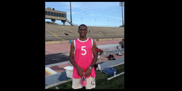 Young athlete in pink sports jersey on a stadium field.