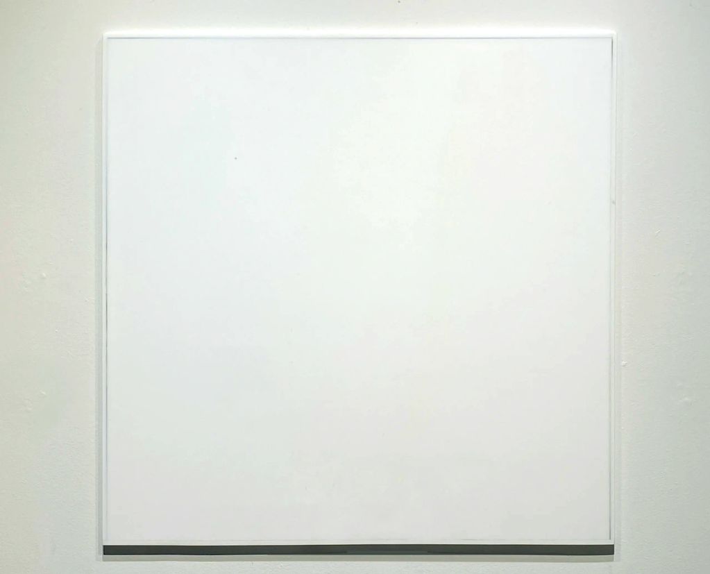 A large blank white square canvas on a wall.
