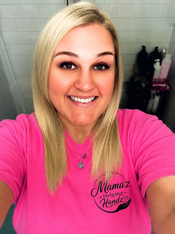 Smiling woman wearing a pink Mama'z Helping Handz shirt.