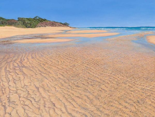 A serene sandy beach with gentle waves and clear blue sky.