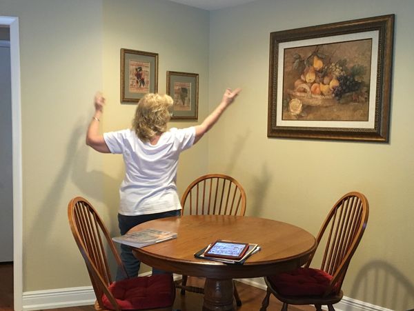 A woman trying to shift an art painting from the room