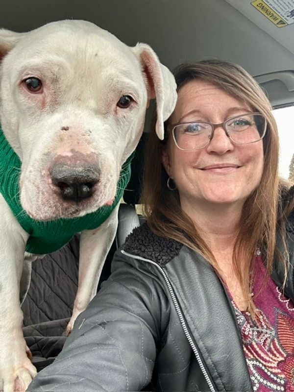 Woman and her dog wearing a green sweater.