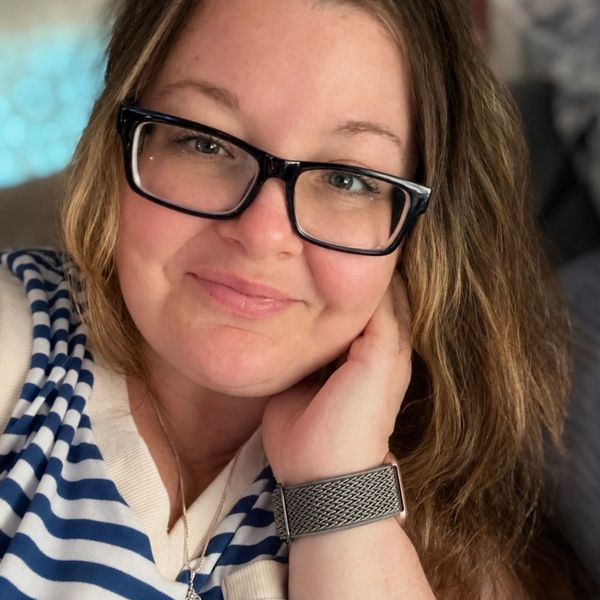Smiling woman with glasses and striped shirt.