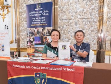 两人在Académie Ste-Cécile国际学校展台签字。
