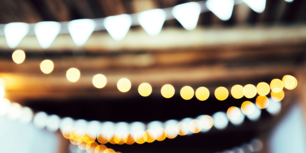 Blurred string lights and triangular flags hanging under a wooden ceiling.