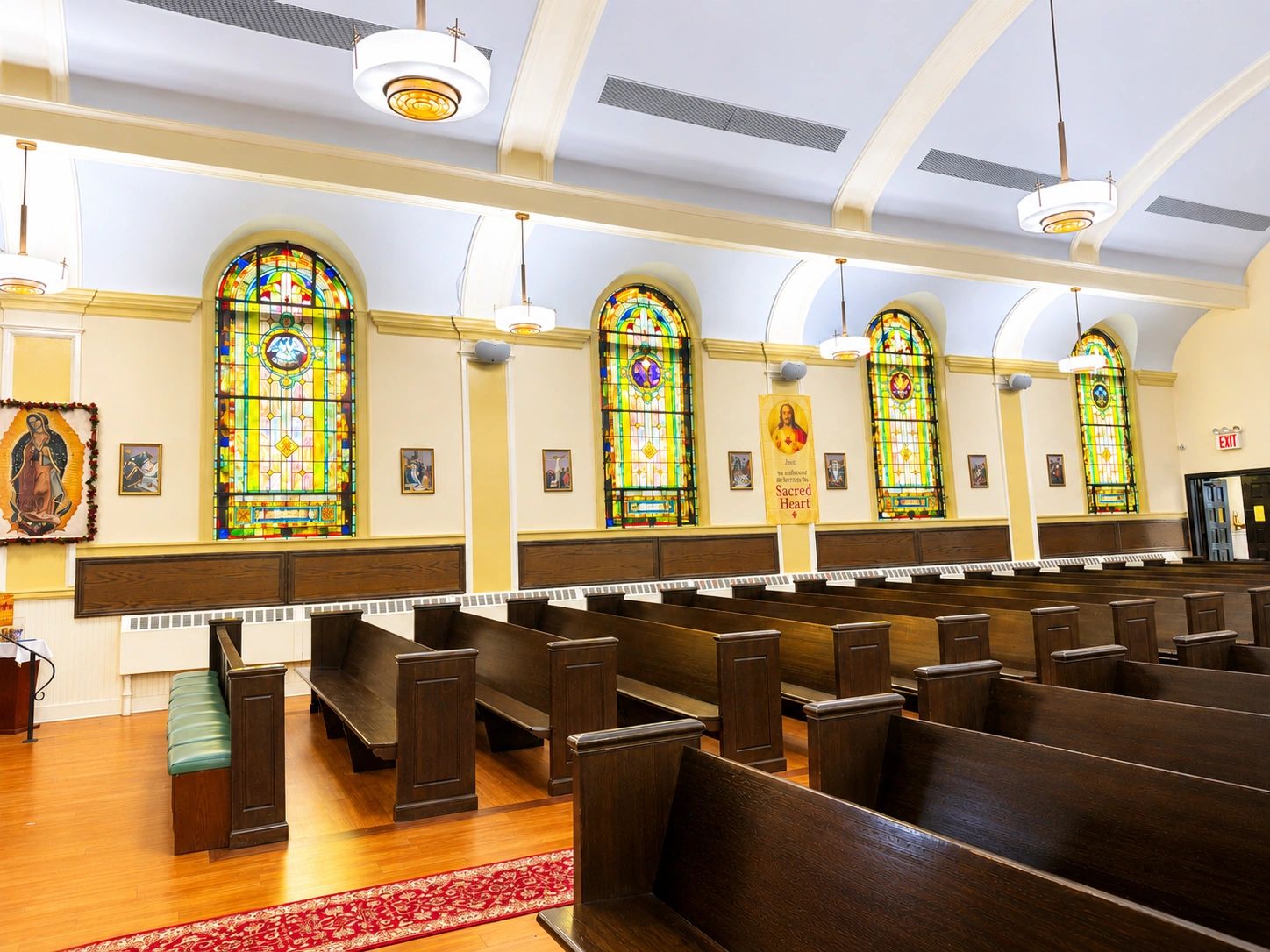 Empty church interior with stained glass windows and wooden pews.