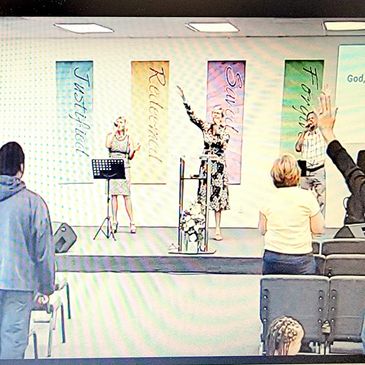 People worshiping with hands raised in a church.