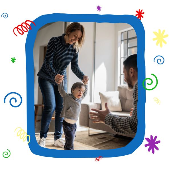 A child taking first steps with support from a smiling woman and a man encouraging.