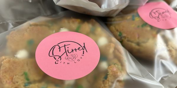 Packaged cookies with pink stickers labeled "Stirred with love."