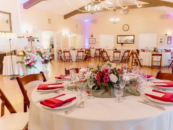 Elegant wedding reception setup with floral centerpiece and red napkins.