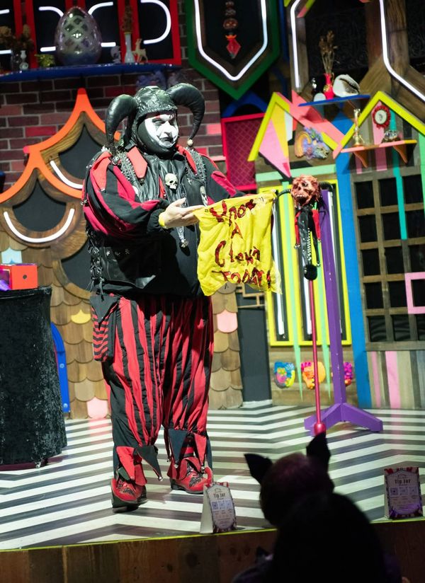 A jester in costume performing on stage.