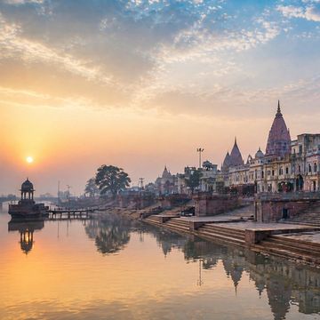 Sunrise over ancient temples and ghats by a river.