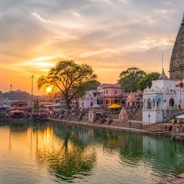 Sunset over the Gaya Ji Pinddaan Ghat with temples and a river reflecting the sky.